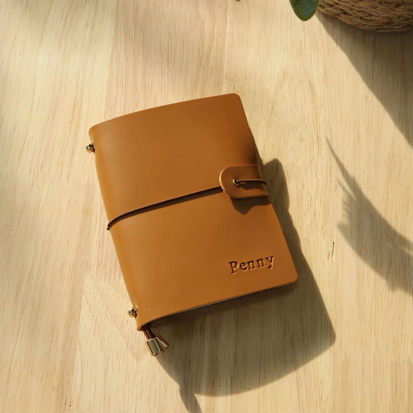 Cognac brown passport holder with wrap strap and metal corner clasp, engraved name Penny