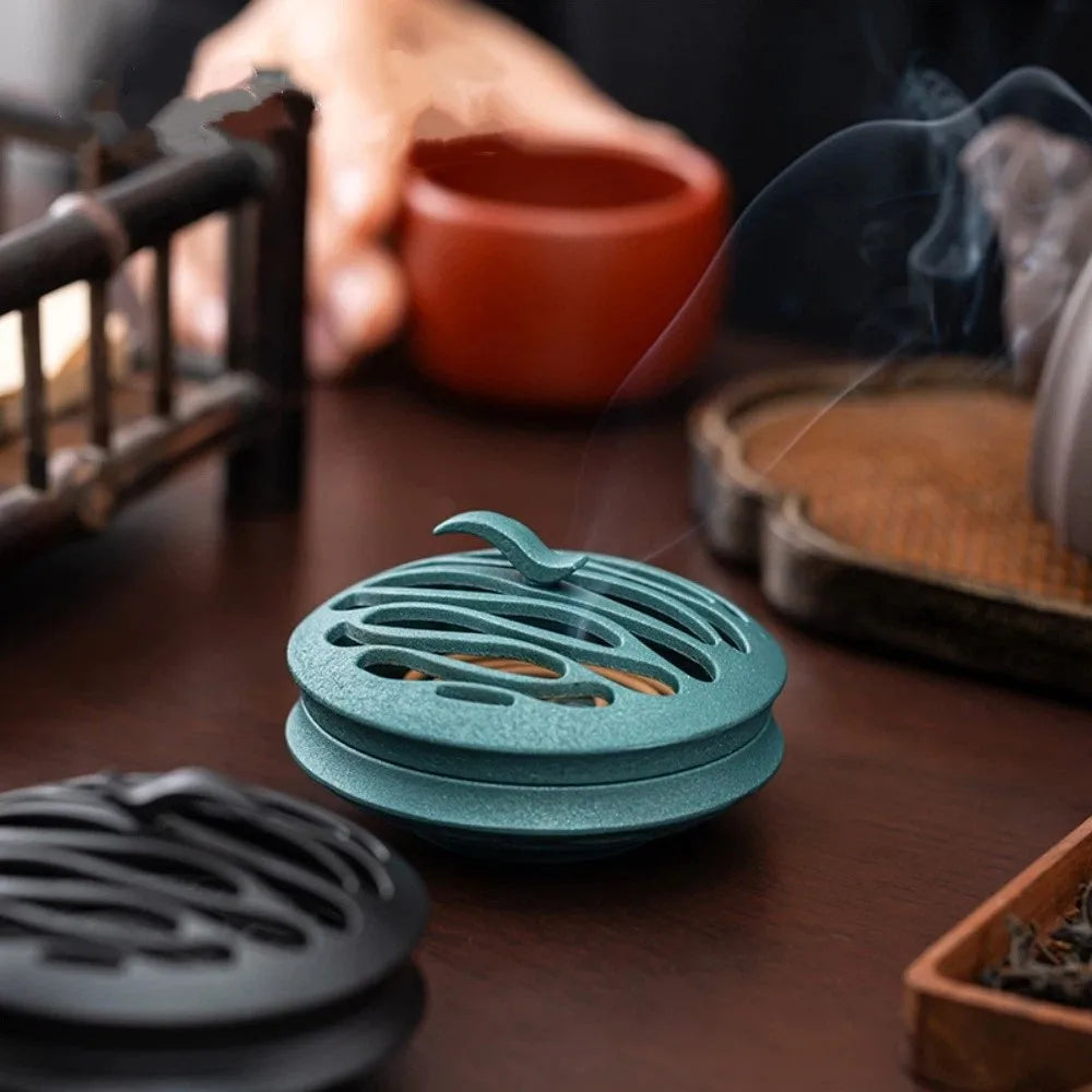Teal/blue round incense burner on tabletop with smoke rising from the cutouts