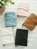 Vegan leather passport holders in light blue, pink, tan, white, and black with buckle straps