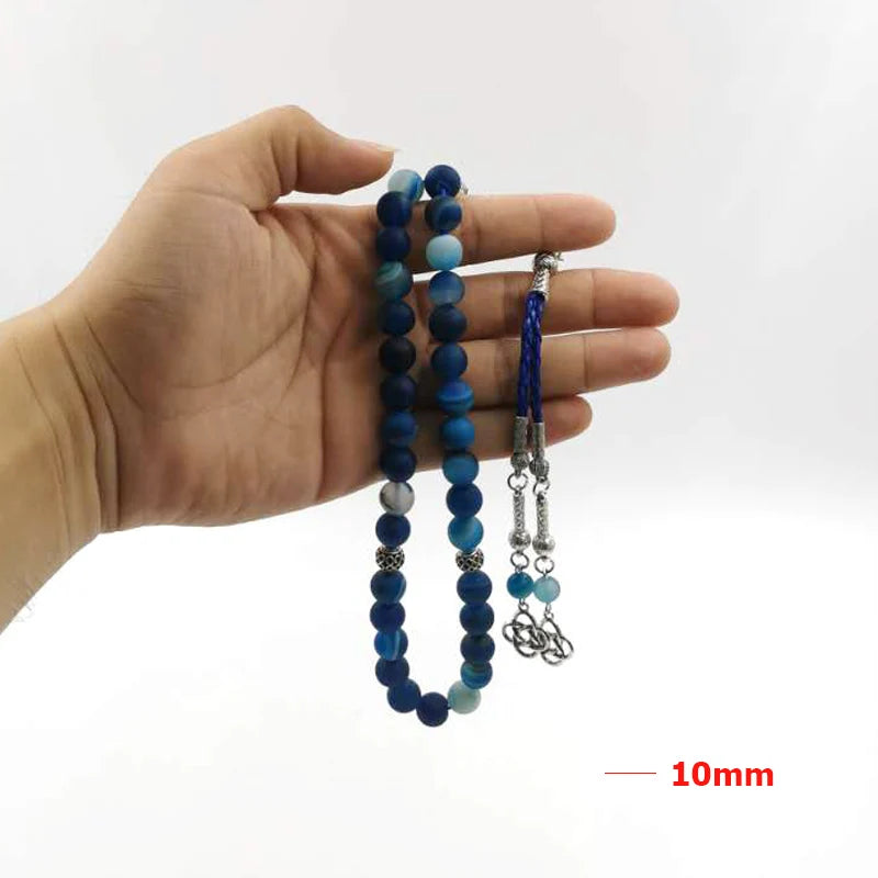 Blue agate prayer beads in hand with silver-tone end pieces and braided tassel