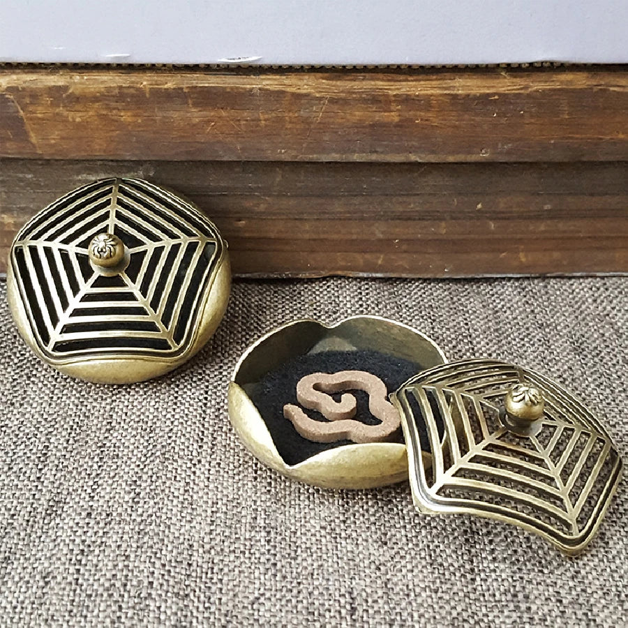 Brass pocket incense burner set with lattice-pattern lid and black insert showing swirl motif