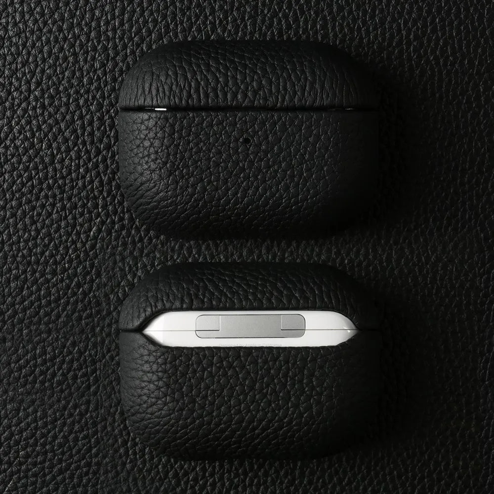 Obsidian black leather AirPods case, closed and bottom edge shows small indicator cutout