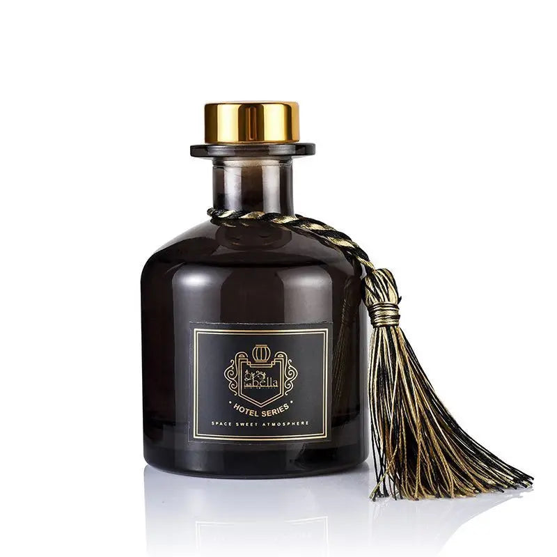 Dark round glass reed diffuser bottle with gold cap and gold tassel
