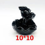 Black glossy backflow incense burner with conical incense holder on a wavy dish