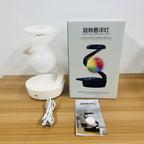 White rotating RGB wireless charging lamp with glowing white orb beside retail box