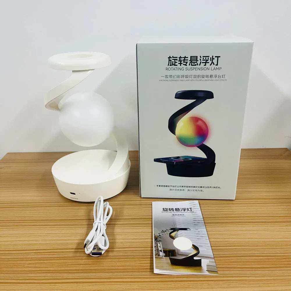 White rotating RGB wireless charging lamp with glowing white orb beside retail box