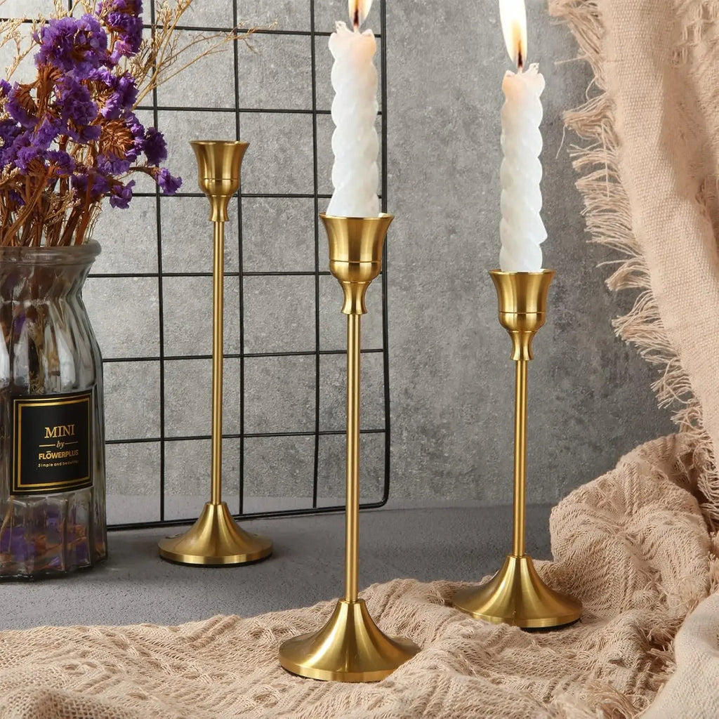 Gold metal candle holder set with three tall stands and fluted bases