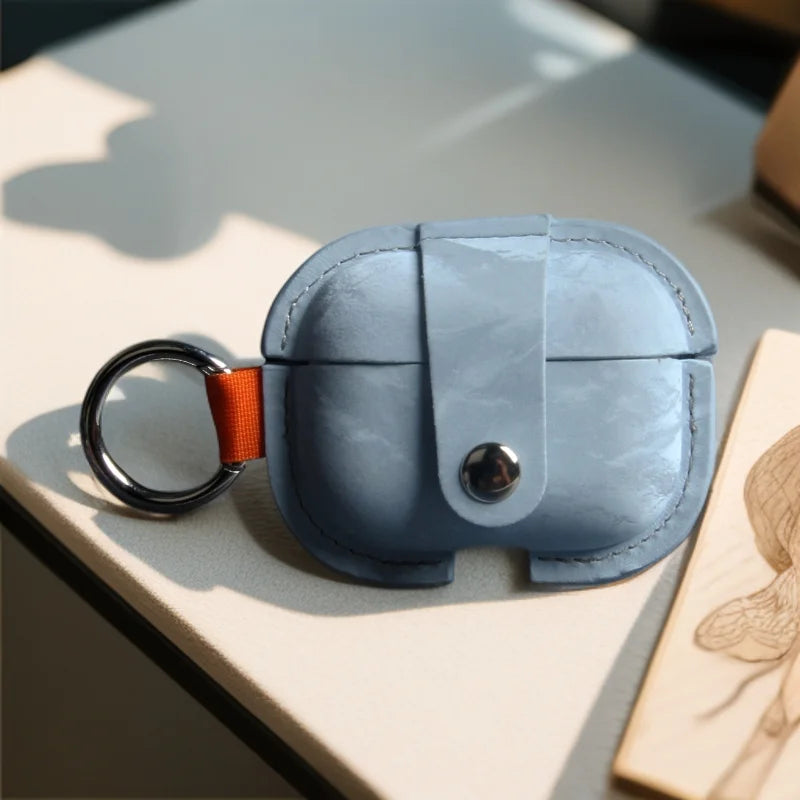 Light blue PU AirPods cover with orange strap, silver key ring, and snap button