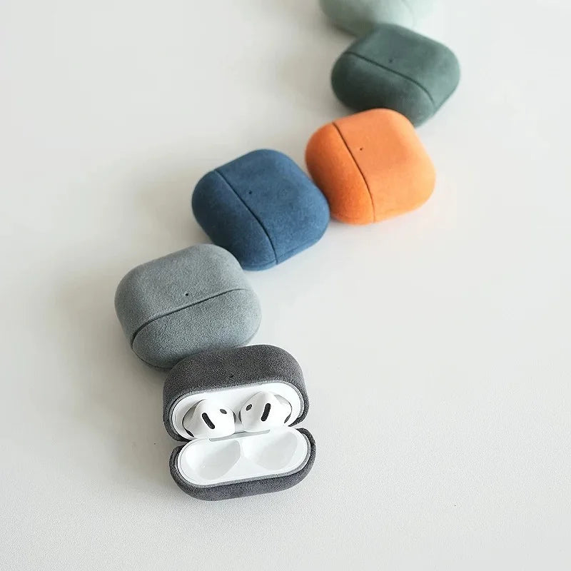 Dark gray Alcantara AirPods case with white AirPods inside; rounded suede texture