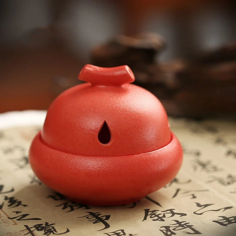 Stone glaze red ceramic incense stove with central oval opening and incense stick