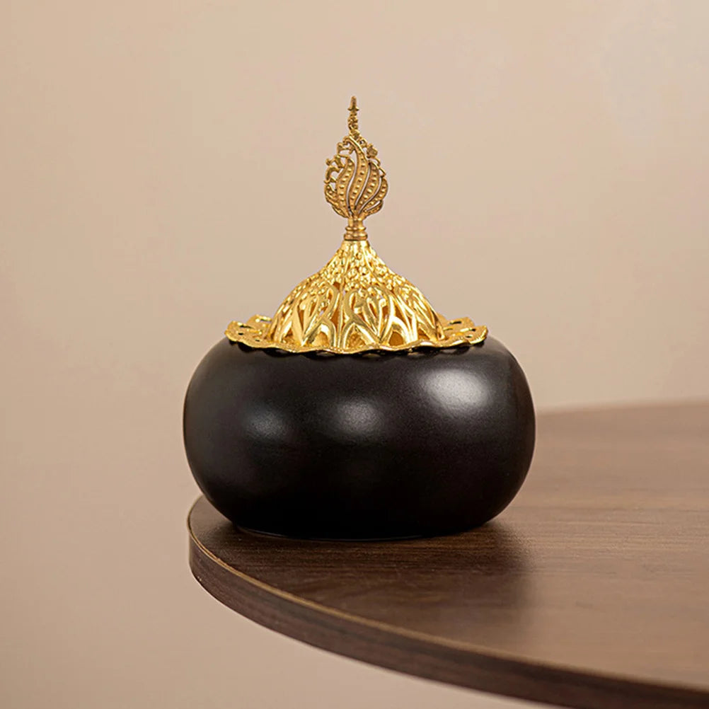 Ceramic oud burner with black dome body and gold finial, ornamental dome lid