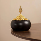 Ceramic oud burner with black dome body and gold finial, ornamental dome lid