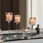 Tall glass candle holder set of 3 with clear stems and round holders, lit candles inside