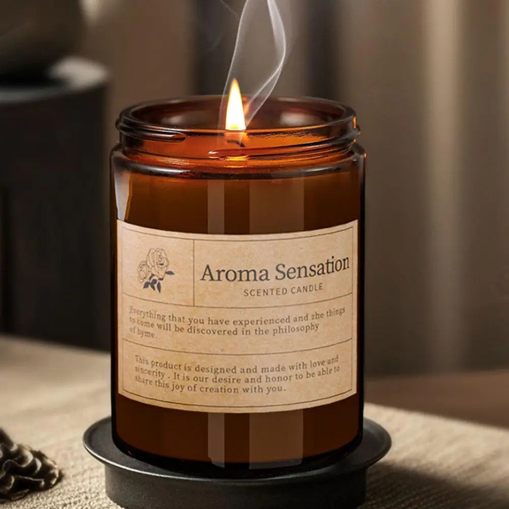 Amber scented candle jar with label and flame, smoke curling upward from wick