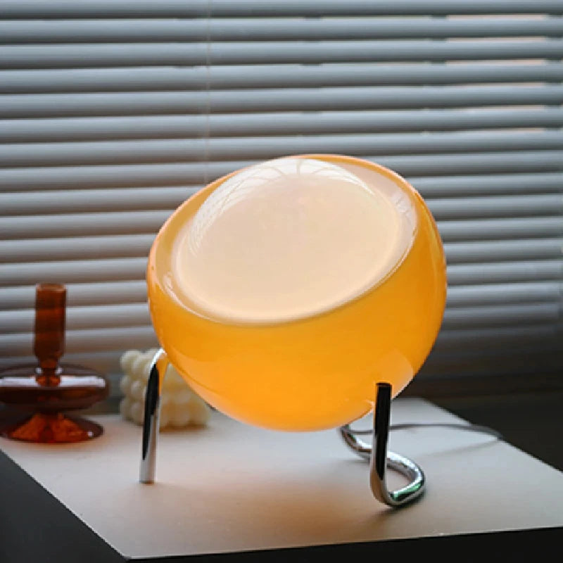 Close-up of amber glass globe lamp with warm internal light and chrome legs