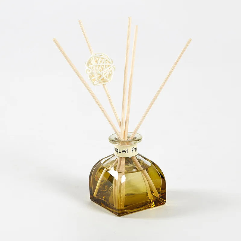 Amber reed diffuser bottle with 5 light wooden reeds and white woven diffuser ball