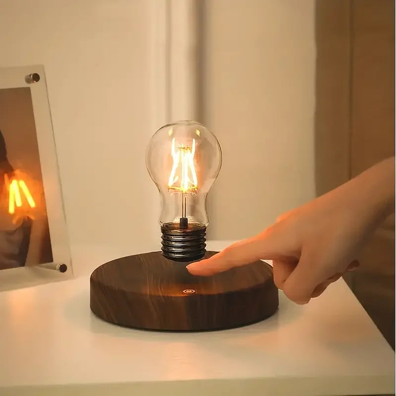 Magnetic night lamp with glowing bulb on round base, finger touching the base