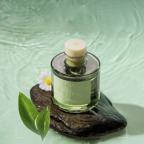 50ml reed diffuser bottle with white cap, green glass, on a smooth stone