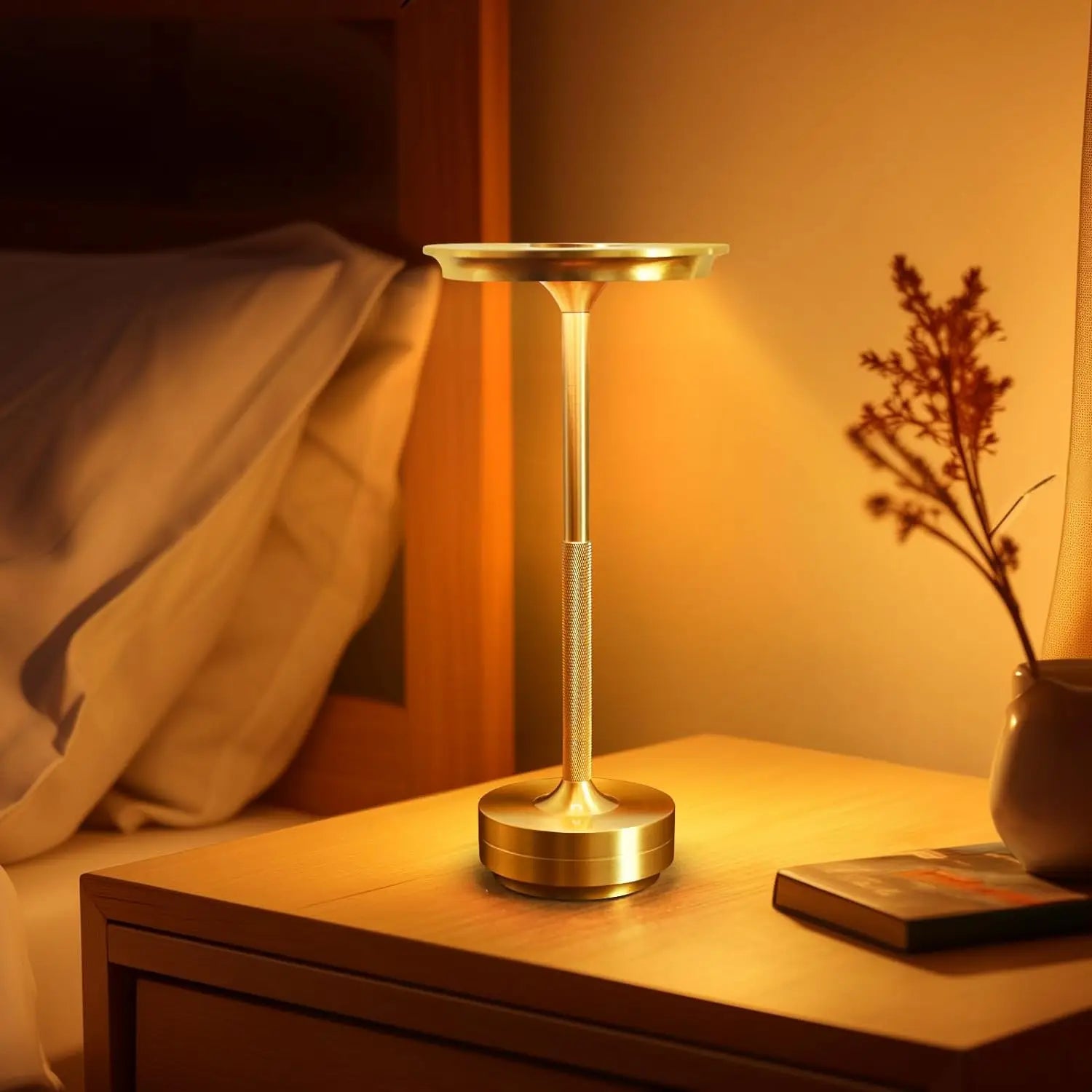 Gold cordless touch reading lamp on a bedside table with warm glow