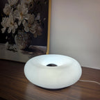 White donut table lamp with center cutout, soft glowing light on a tabletop