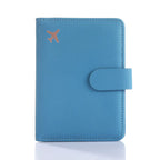 Blue passport folio with embossed airplane icon, snap strap closure, and stitched borders