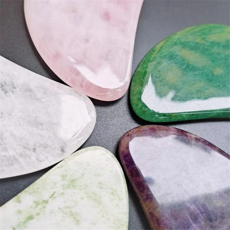 Close-up view of heart-shaped jade roller stones in green, pink, white, and purple tones.