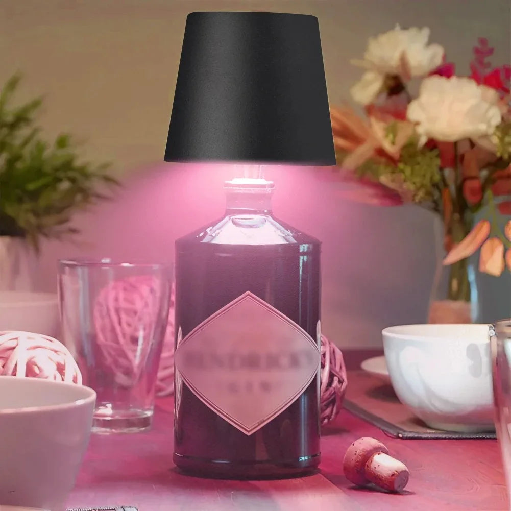 Black wine bottle LED lamp glowing pink light above a bottle