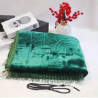 Velvet padded prayer rug in deep green with raised arch design and long fringe trim.