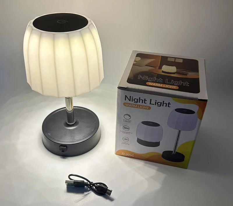 Cordless LED table lamp with white shade, black base, and included charging cable