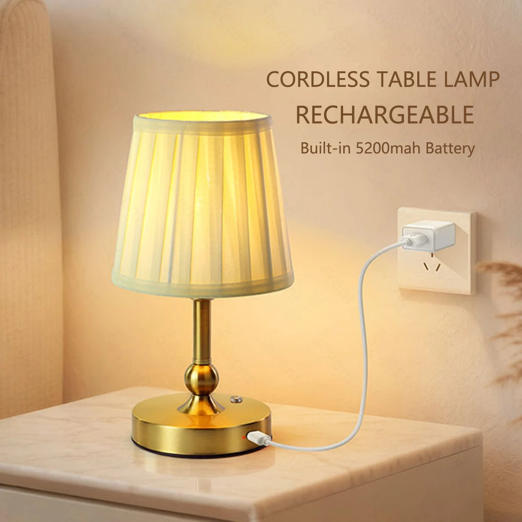Cordless rechargeable table lamp with champagne gold ribbed shade on base; charging plugged in