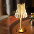 Cordless table lamp with gold base and pleated glass shade, warm glow