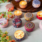 Multiple flame-lit vintage jar scented candles with colorful patterned lids on tabletop