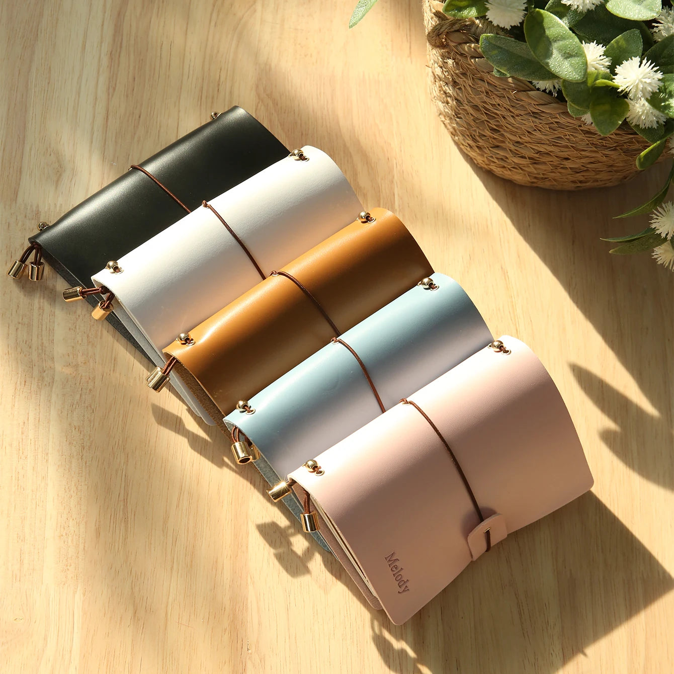 Assorted vegan leather passport holders with clasp straps in dark, white, tan, and pastel colors