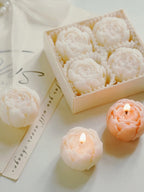 White rose-shaped soy wax candles in gift box with peach candle outside
