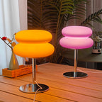 Mushroom USB ambient table lamp on wooden table, glowing orange and pink beside plants.