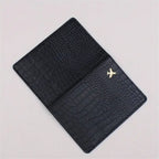 Black croc-embossed passport sleeve with gold airplane logo, front close view