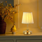 Champagne gold cordless table lamp with ribbed shade glowing; rounded brass base