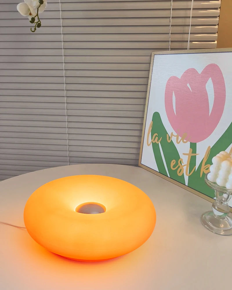 Yellow-orange donut table lamp glowing on a tabletop