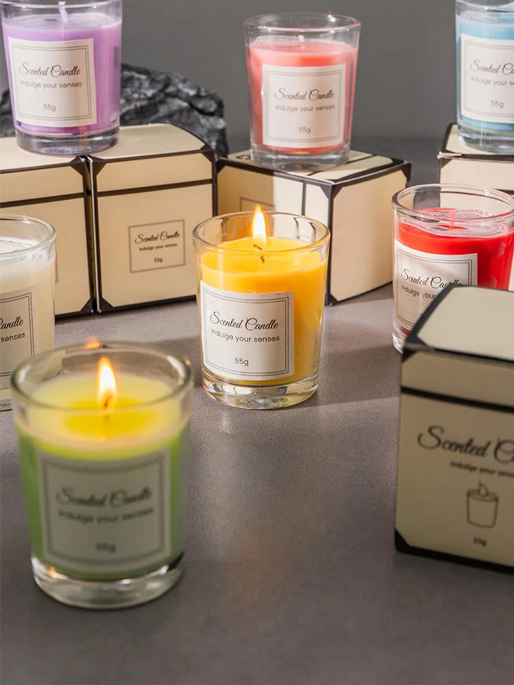 Assorted colored glass scented candles with lit wicks and gift boxes