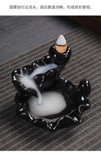 Tower backflow incense burner with incense cone rising from black-and-white glaze