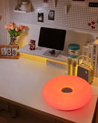 Orange donut table lamp glowing on a counter with round center opening