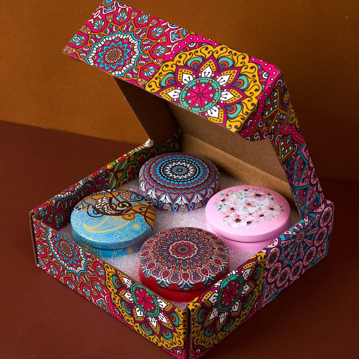 Geöffnetes Geschenkset mit 4 Duftkerzen in Mandala-Design: blau, lila, rot, violett