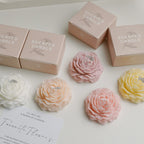 Peony sculptural candles in soft colors with labeled gift boxes, pink and yellow on display