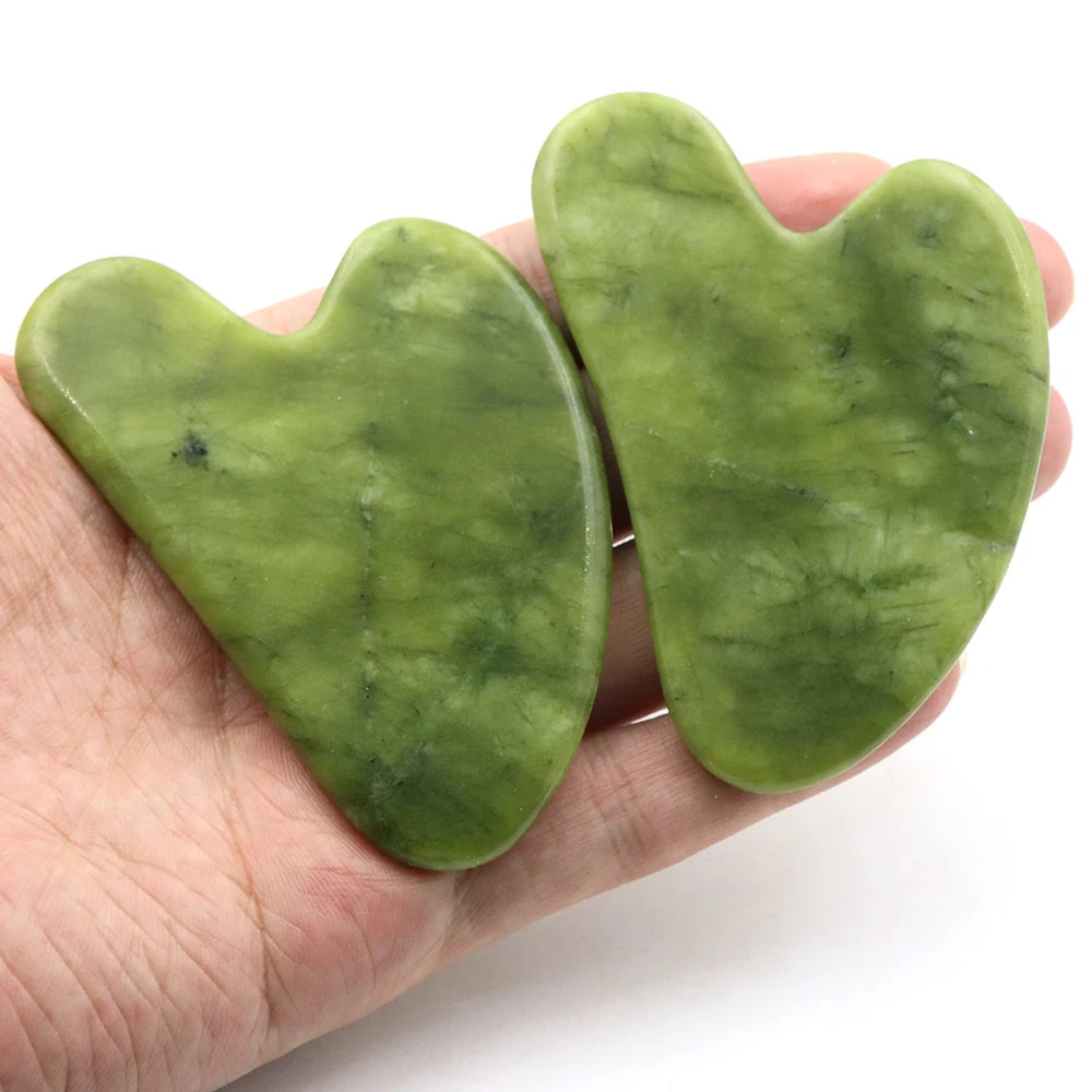 Heart-shaped green jade scraper held in hand, polished curved edge