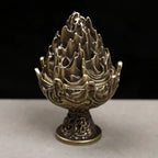 Copper-toned incense censer close-up with carved flame-lotus top and decorative pedestal base.