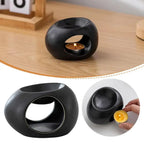 Black ceramic aroma oil burner on wood surface with lit tea candle