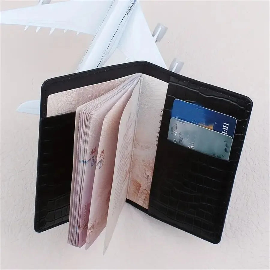 Black passport sleeve with gold plane, open card slots for travel documents