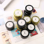 Assorted soy wax candles in tins, gold and black lids; labels on top