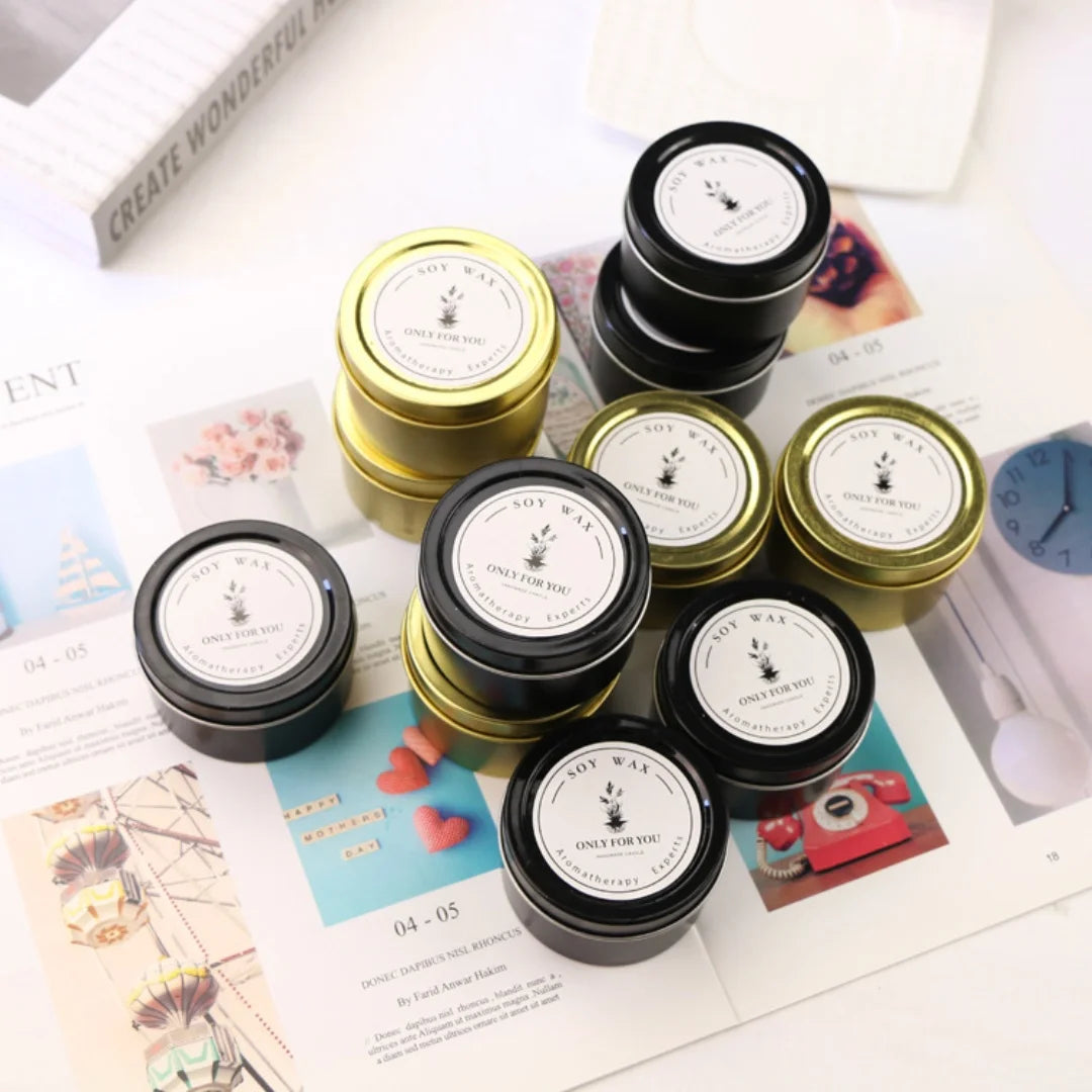 Assorted soy wax candles in tins, gold and black lids; labels on top
