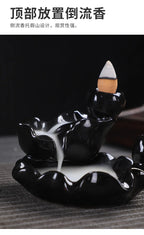 Tower backflow incense burner with curling smoke streams and white cone tip